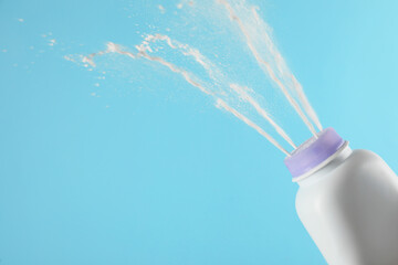 Scattering of dusting powder on light blue background, space for text