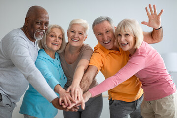 Multiracial group of athletic senior people placing hands - obrazy, fototapety, plakaty
