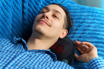 Electric massage cushion with infrared warming areas. Milineal man relaxes at home