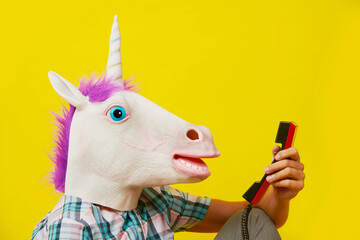 man with a unicorn mask talking on a red phone