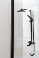 Black shower faucet in cabin in bathroom with white walls