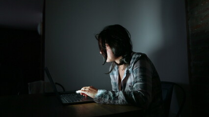 Woman staring at laptop screen at night alone at apartment home