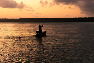 Silhouette of a fisherman and his small wooden boat on a lake