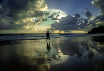 White man standing on a beach during sunrise.