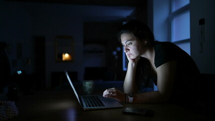 Woman browsing internet in front of laptop screen at night