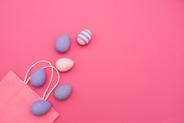 Easter purple eggs from a paper pink bag on a pink background. Easter eggs in a paper bag. easter card. Easter ideas. Place for text.