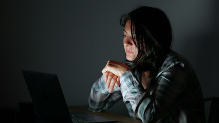 Person reading content online at night in front of laptop screen