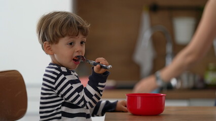 Pensive toddler child eating strawberry fruit snack with fork