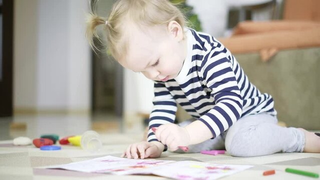 Cute concentrated little kid girl is drawing of color pencil play alone on floor. Children playtime education concept