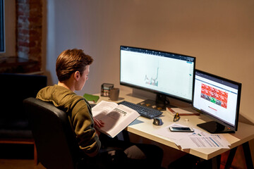 Male trader reading book during working at desk