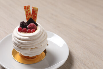 Delicious meringue dessert with berries on wooden table, closeup. Space for text