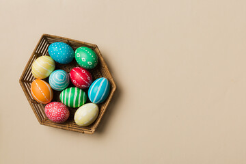 Multi colors Easter eggs in the woven basket on colored background . Pastel color Easter eggs. holiday concept with copy space