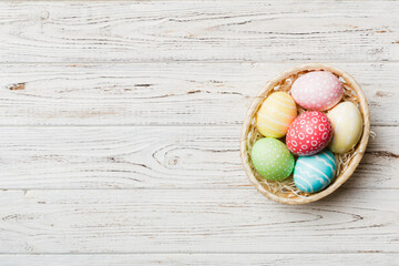 Multi colors Easter eggs in the woven basket on colored background . Pastel color Easter eggs. holiday concept with copy space