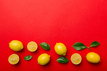 Many fresh ripe lemons with green leaves on colored background, top view, space for text