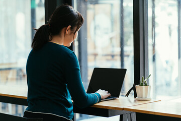 Pretty female student with cute smile keyboarding something on laptop while relaxing after lectures in University, beautiful happy woman working on laptop computer during coffee break in cafe bar.