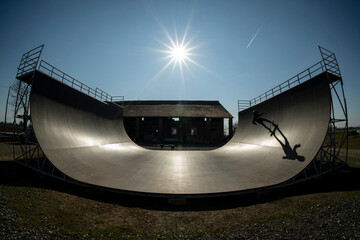 Young skateboarder in action, on a vert ramp with big shadow