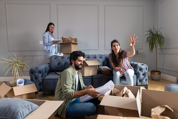 Roommates agree on how to decorate the apartment while looking at the blueprint and unpacking things