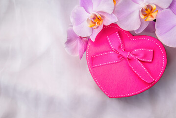 gift box in the form of heart and an orchid on white fabric