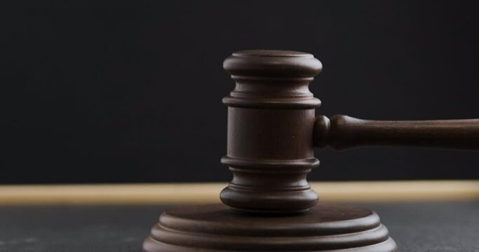 Judge pronouncing sentence striking wooden gavel. Judge hitting hammer against hardwood on black background.