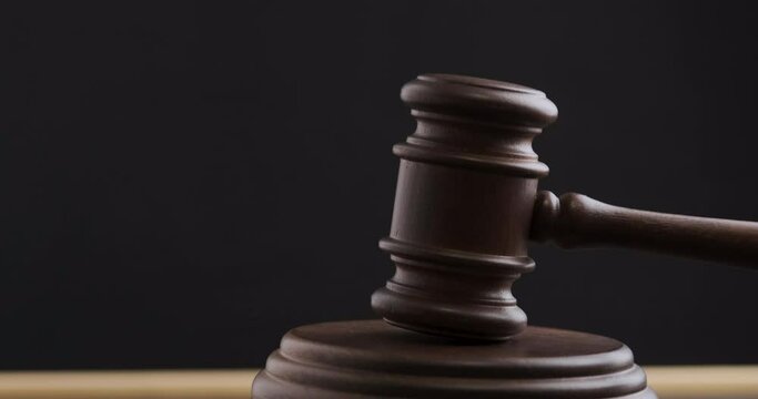 Judge hitting hammer against hardwood. Judge pronouncing sentence striking wooden gavel. Black background.