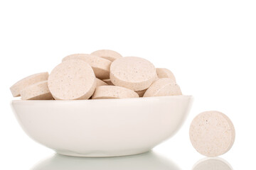 Several medical tablets on a ceramic white saucer, macro, isolated on a white background.