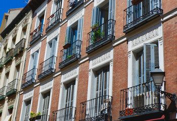 Fototapeta na wymiar Classical facades of pastel colours and vintage balconies with shutters in Sol district downtown Madrid, Spain