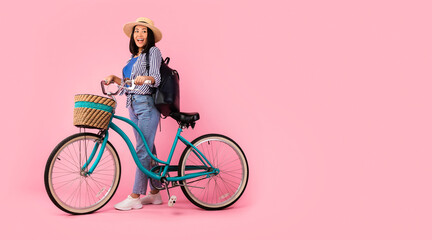 Excited asian woman standing with retro bicycle with wicker basket
