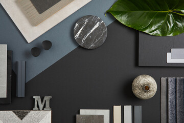 Elegant flat lay composition of interior designer moodboard with textile and paint samples, panels and tiles. Black, blue, beige and dark grey color palette. Copy space. Template.