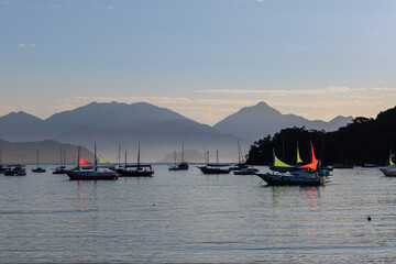 boats moored on the coast at dawn with blue sky and mountains in the background