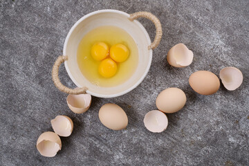 Whole eggs, broken eggs, yolk in a bowl on the table. Selective focus