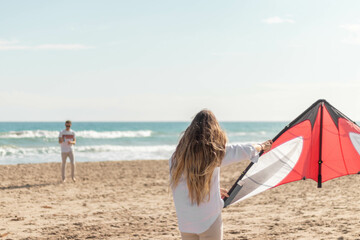 Young woman holding a kite and playing on the mediterranean coast