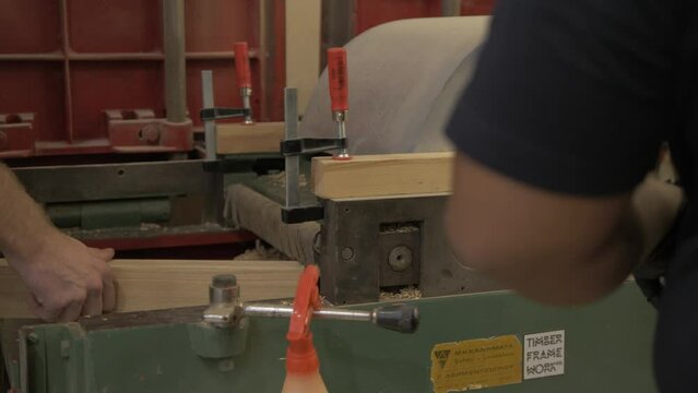 Woodworkers passing white oak timber through planer thicknesser machine