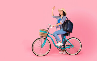 Excited asian woman riding retro bicycle with wicker basket