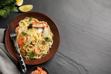 Delicious pasta with sea food served on black table, flat lay. Space for text