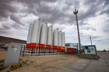 Mangystau, Kazakhstan - May 19 2012: Bautino bay. Oil loading terminal on Caspian sea. Storage tanks and mast. Grey storm clouds.