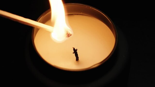 candle being lit and ignited by a wooden match stick, black background