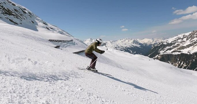 Young ski athlete skiing downhill on a steep ski run in the austrian alps with beautiful view. Rhythmic short turn skiing with great ski style in tirol austria. Great light fresh snow 4K follow camera