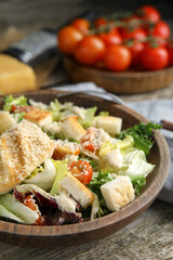 Delicious Caesar salad in bowl on wooden table, closeup