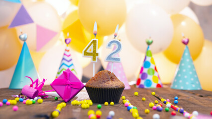 Happy birthday with a number of candles for forty-two years on the background of balloons. A...