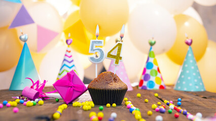 Happy birthday with a number of candles for fifty-four years on the background of balloons. A...