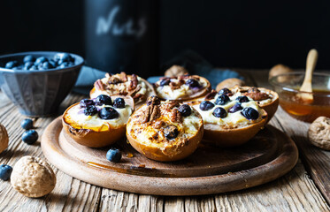 Backed pears with ricotta cheese, blueberries, pecan nuts and honey in rustic style concept