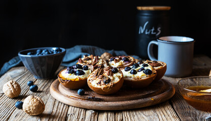 Backed pears with ricotta cheese, blueberries, pecan nuts and honey in rustic style concept