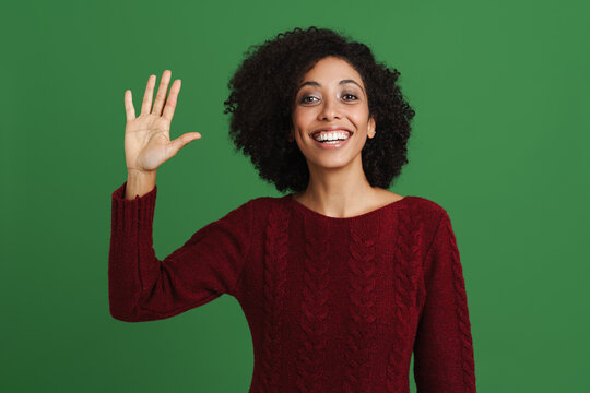Black young woman smiling and waving hand at camera