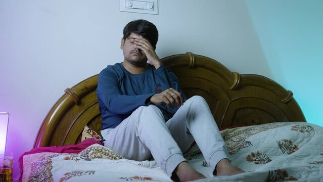 pan shot of young man thinking deep while sleeping on bed at night - concept of debt, break-up and sleeplessness and insomnia