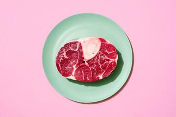 Raw beef steak above view on a pink background.