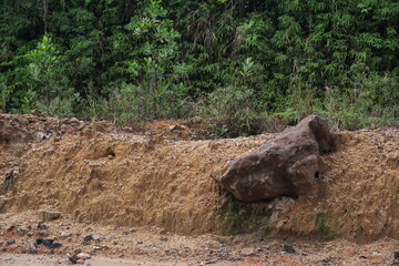 is a large stone located on an embankment or median made of soil
