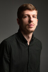 Fototapeta premium Portrait of young blond european man with short beard and mustache isolated on dark grey in black shirt