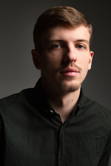 Obraz premium Portrait of young blond european man with short beard and mustache isolated on dark grey with shadow on his face