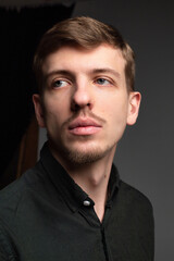 Young blond european man with short beard and mustache isolated on dark grey portrait