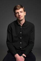 Young blond european man with short beard and mustache isolated on dark grey